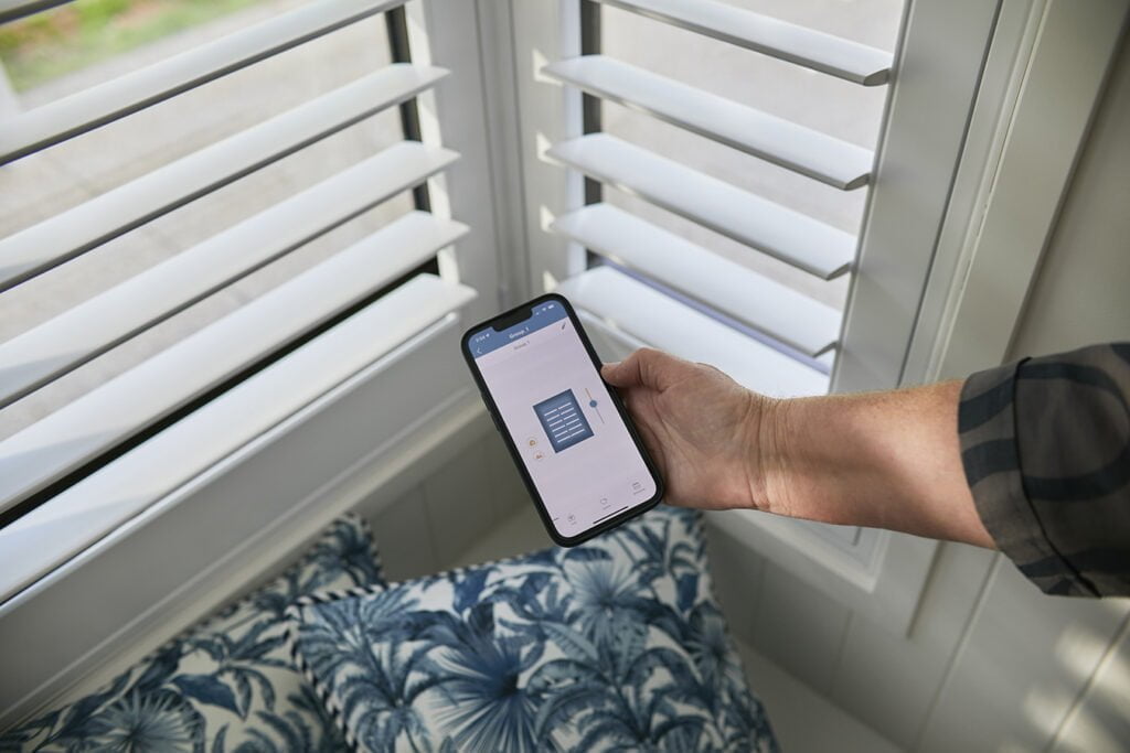 Close-up of Norman’s Motorised Shutters being controlled through the ShadeAuto App on a smartphone. This smart home solution combines convenience and style, allowing precise light and privacy adjustments with a simple touch.